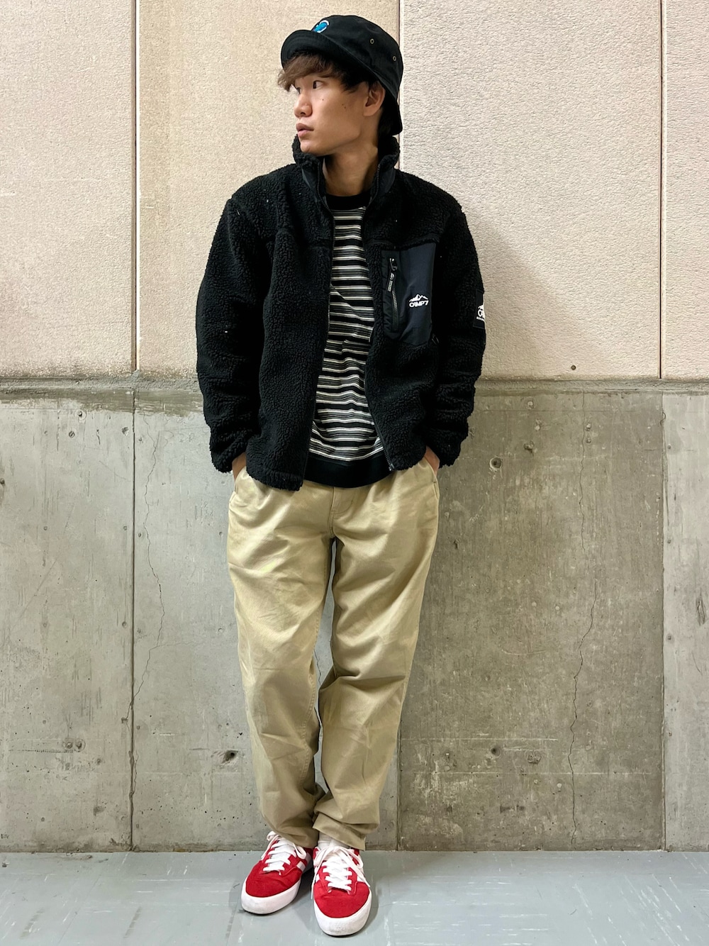 ベージュ系のカーゴパンツ、レッド系のスニーカー、ブラック系のブルゾンを着用したメンズの秋コーディネートの1枚目の写真