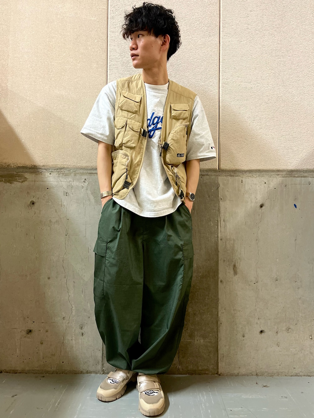 グリーン系のカーゴパンツ、ベージュ系のスニーカー、ベージュ系のベストを着用したメンズの夏コーディネートの1枚目の写真