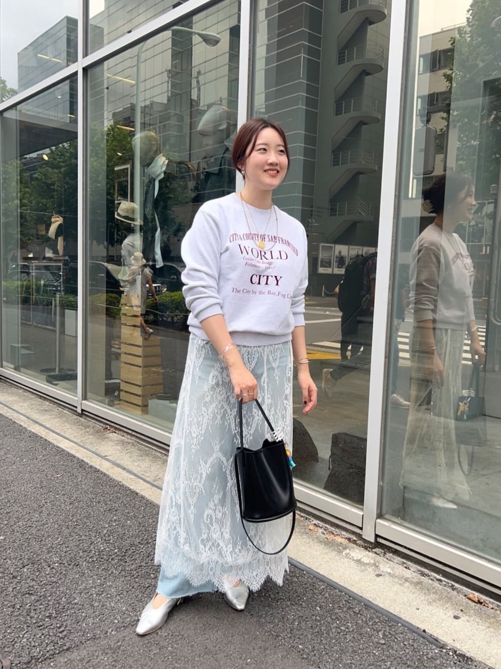 グレー系のTシャツ/カットソー、ブラック系のスカート、ブルー系のデニムパンツを着用したレディースの秋コーディネートの1枚目の写真