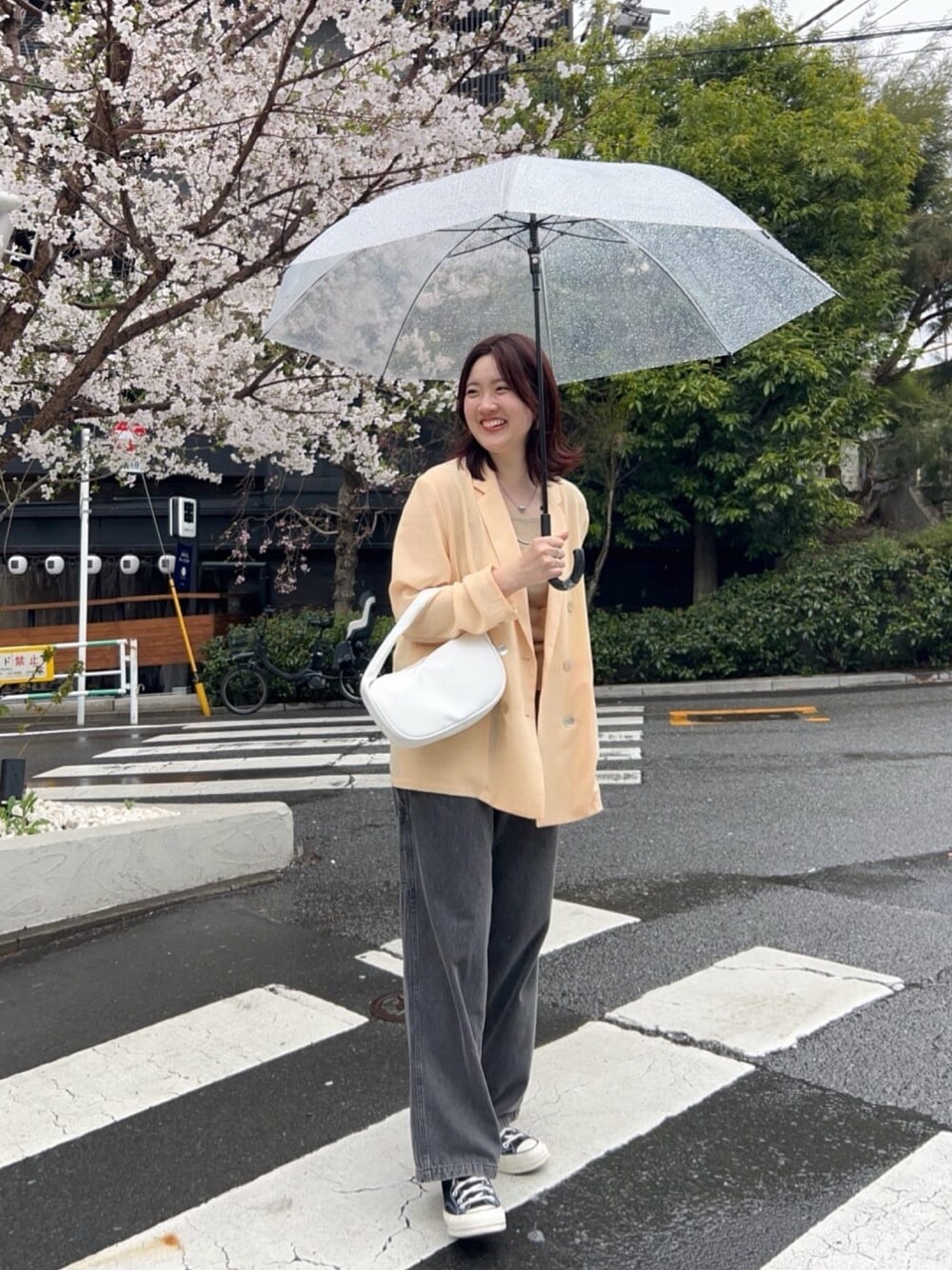 イエロー系のテーラードジャケット、ブラック系のデニムパンツ、シルバー系のネックレスを着用したレディースの春コーディネートの1枚目の写真