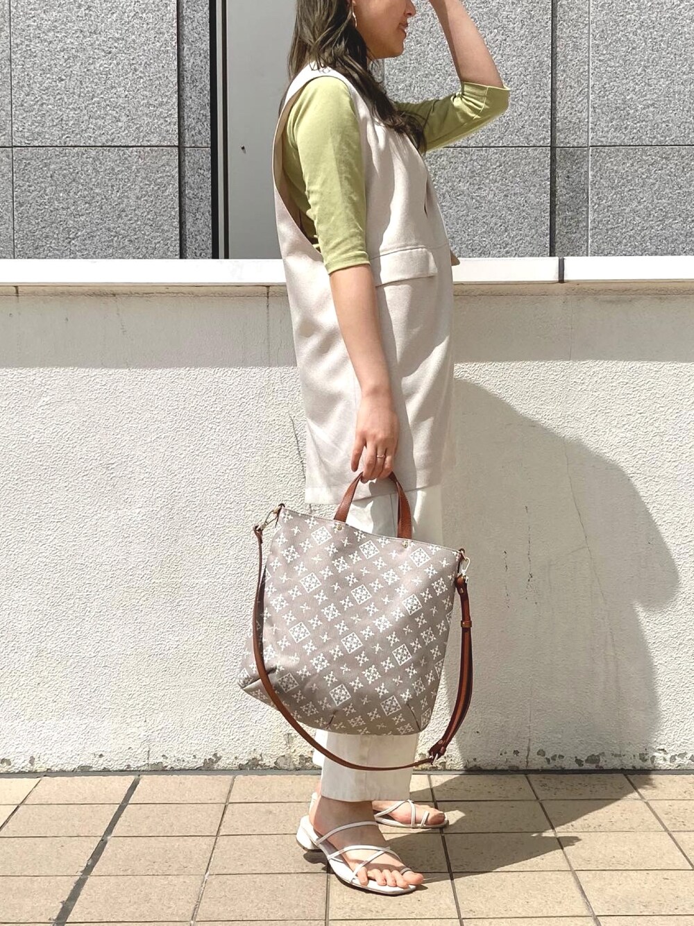 ベージュ系のトートバッグ、ホワイト系のデニムパンツ、ホワイト系のサンダルを着用したレディースの夏コーディネートの3枚目の写真