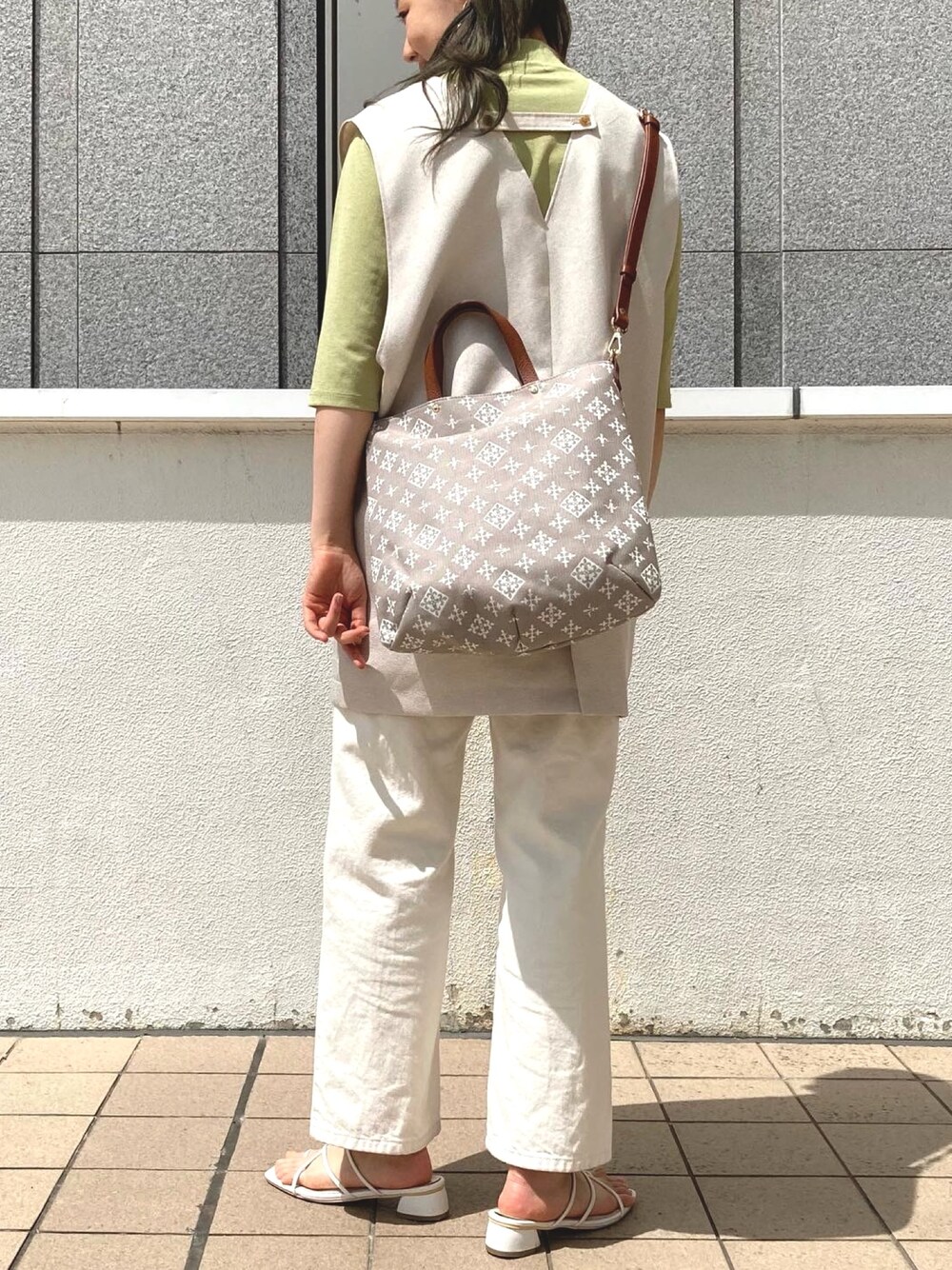 ベージュ系のトートバッグ、ホワイト系のデニムパンツ、ホワイト系のサンダルを着用したレディースの夏コーディネートの2枚目の写真