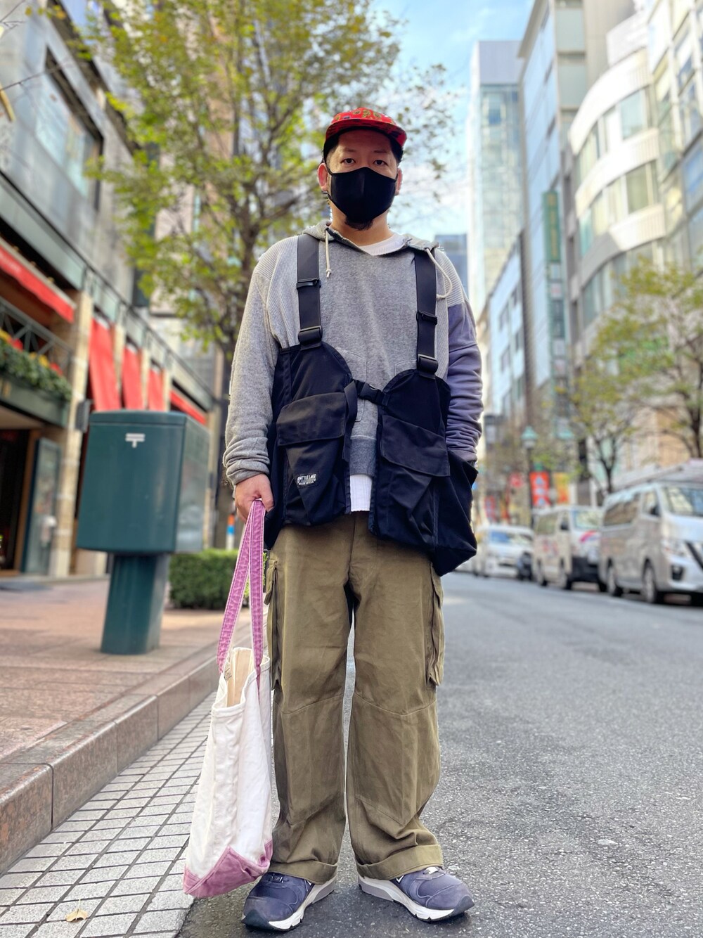グレー系のパーカー、ブラック系のベスト、ブラウン系のカーゴパンツを着用したメンズの秋コーディネートの1枚目の写真
