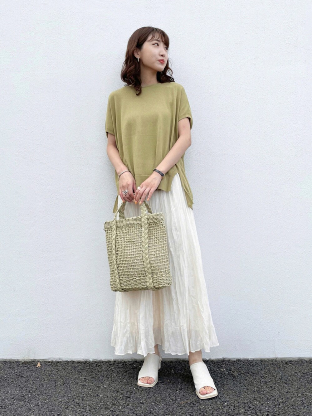 イエロー系のニット/セーター、ホワイト系のスカート、ブラック系のサンダルを着用したレディースの夏コーディネートの1枚目の写真