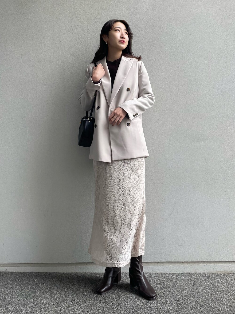 ベージュ系のテーラードジャケット、ブラウン系のニット/セーター、ブラック系のブーツを着用したレディースの冬コーディネートの1枚目の写真