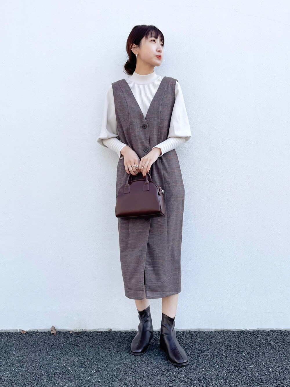 ホワイト系のニット/セーター、ブラウン系のジャンパースカート、ブラウン系のショルダーバッグを着用したレディースの秋コーディネートの1枚目の写真