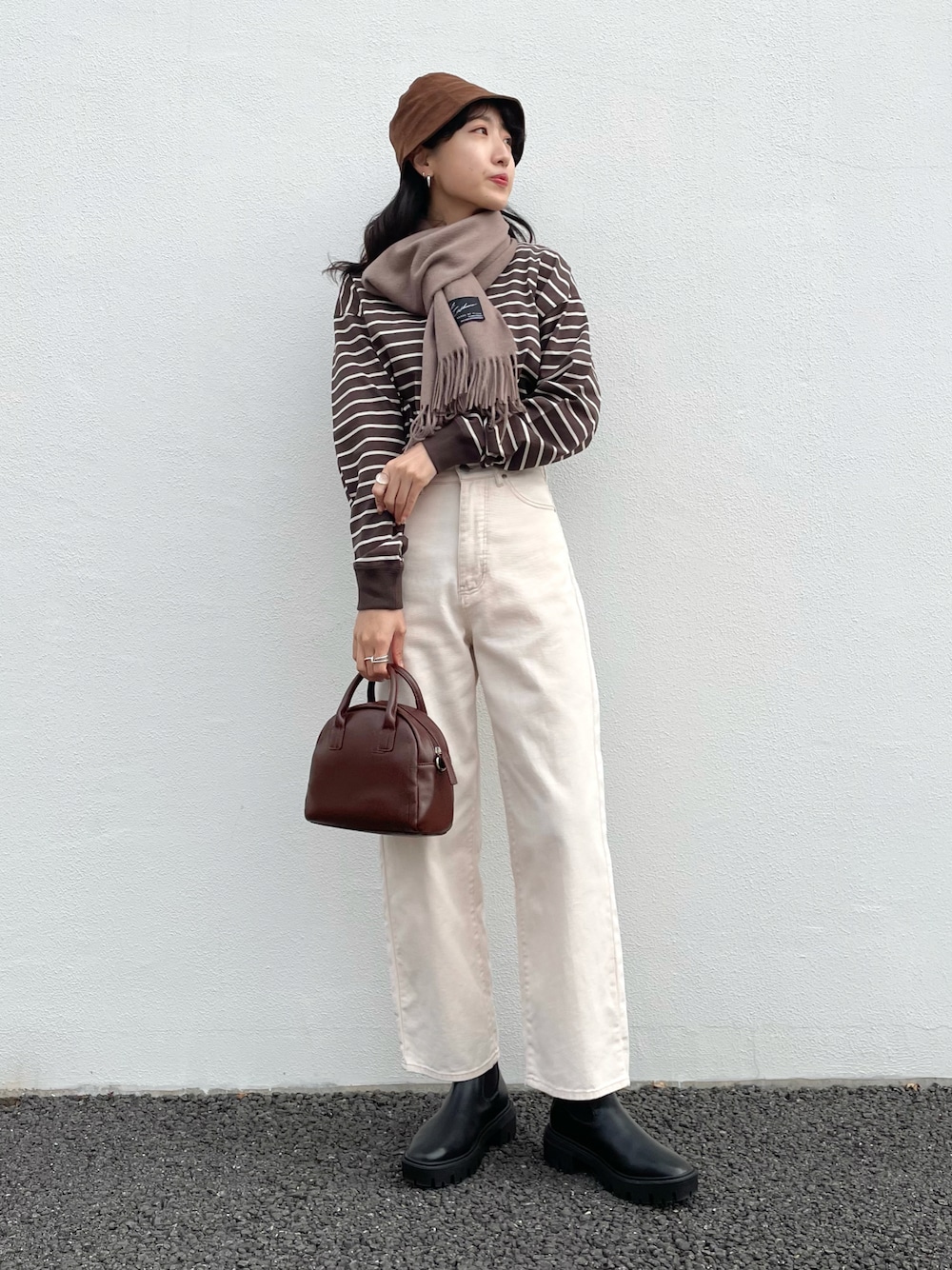 ブラック系のTシャツ/カットソー、ホワイト系のデニムパンツ、ブラウン系のショルダーバッグを着用したレディースの冬コーディネートの1枚目の写真