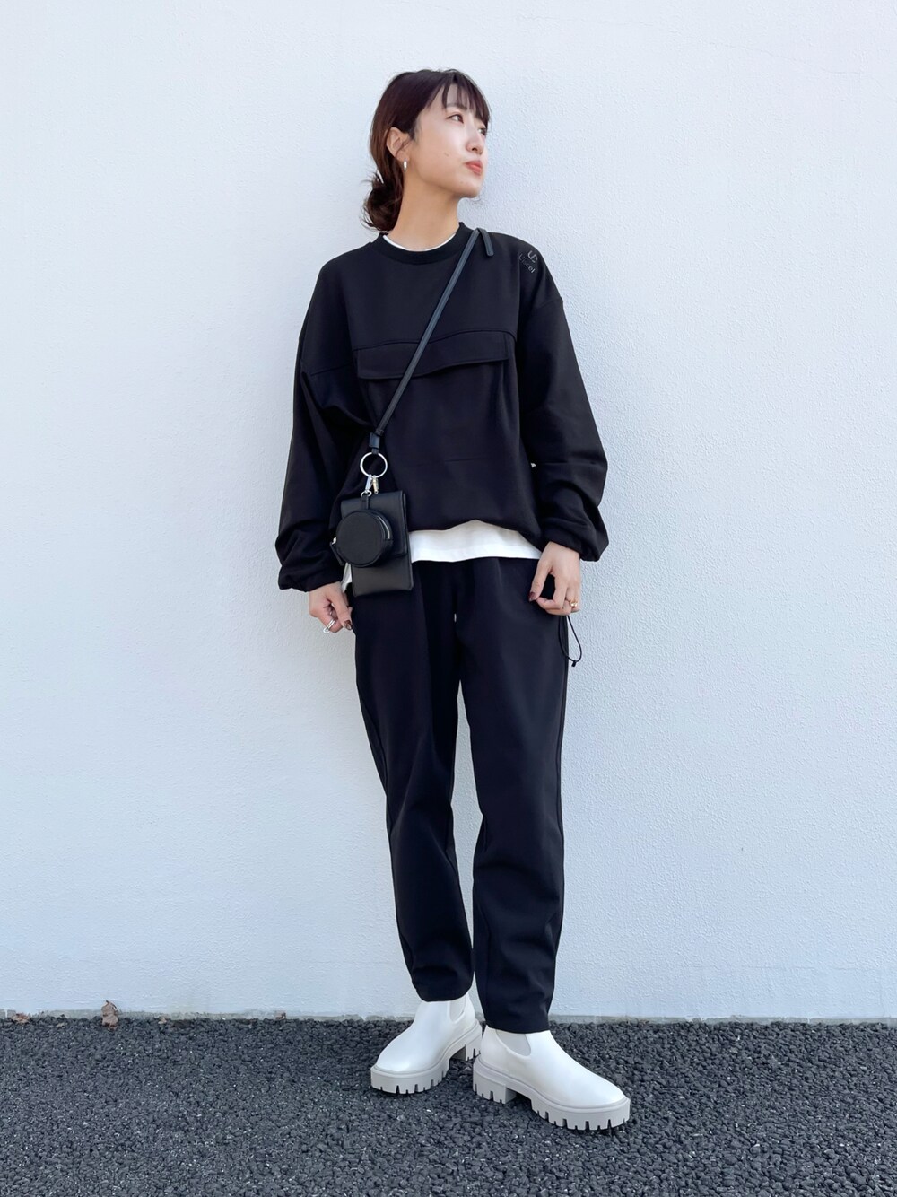 ブラック系のスウェット、ベージュ系のTシャツ/カットソー、ブラック系のブーツを着用したレディースの秋コーディネートの1枚目の写真