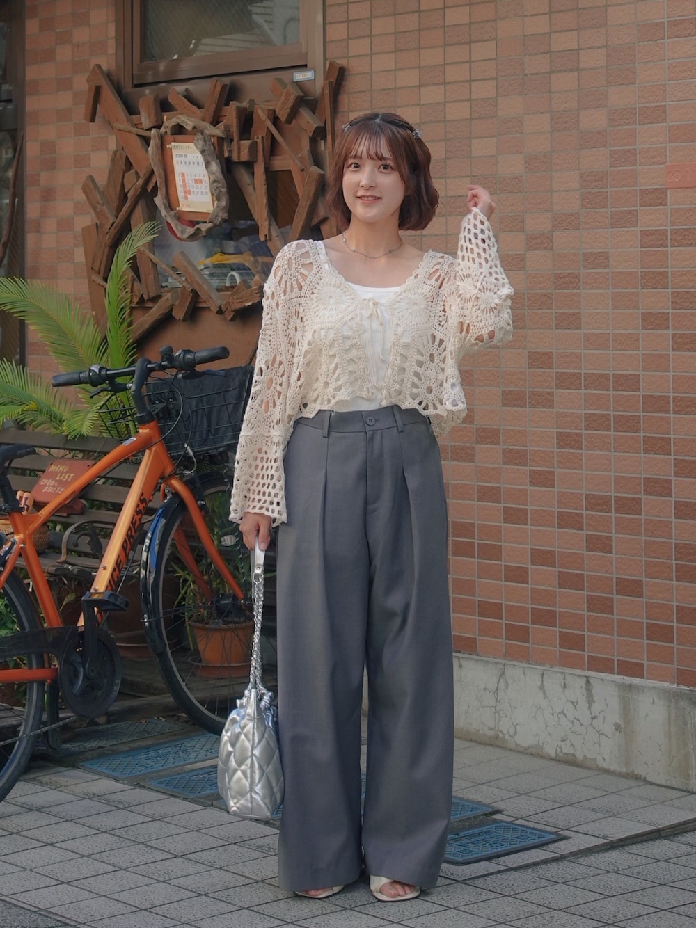 グレー系のスラックス、シルバー系のトートバッグ、ベージュ系のカーディガン/ボレロを着用したレディースの夏コーディネートの1枚目の写真