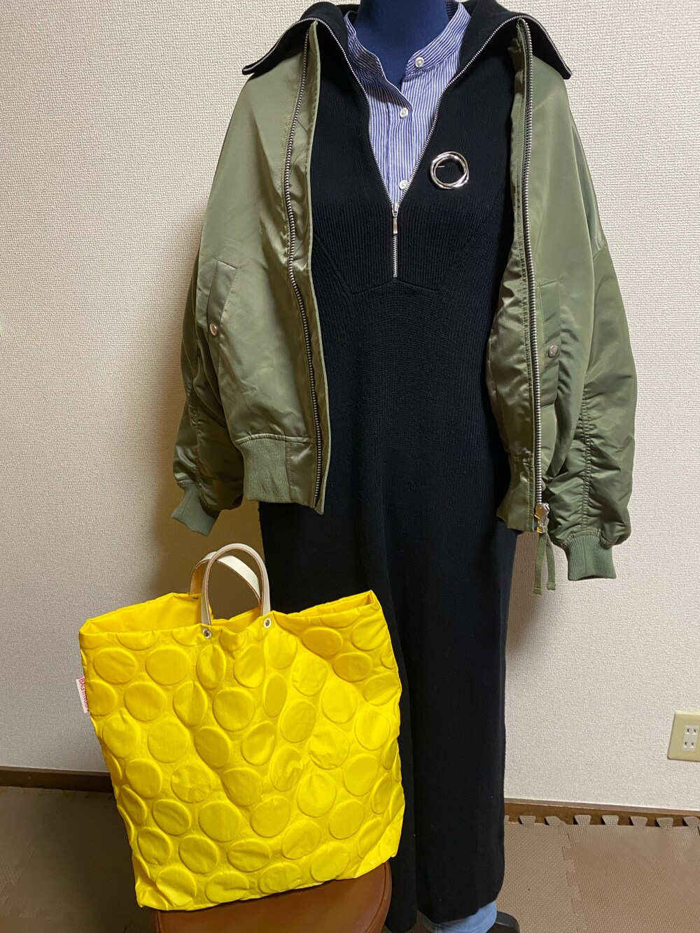 イエロー系のバッグ、ブラック系のワンピース、ブルー系のその他パンツを着用したレディースの春コーディネートの1枚目の写真