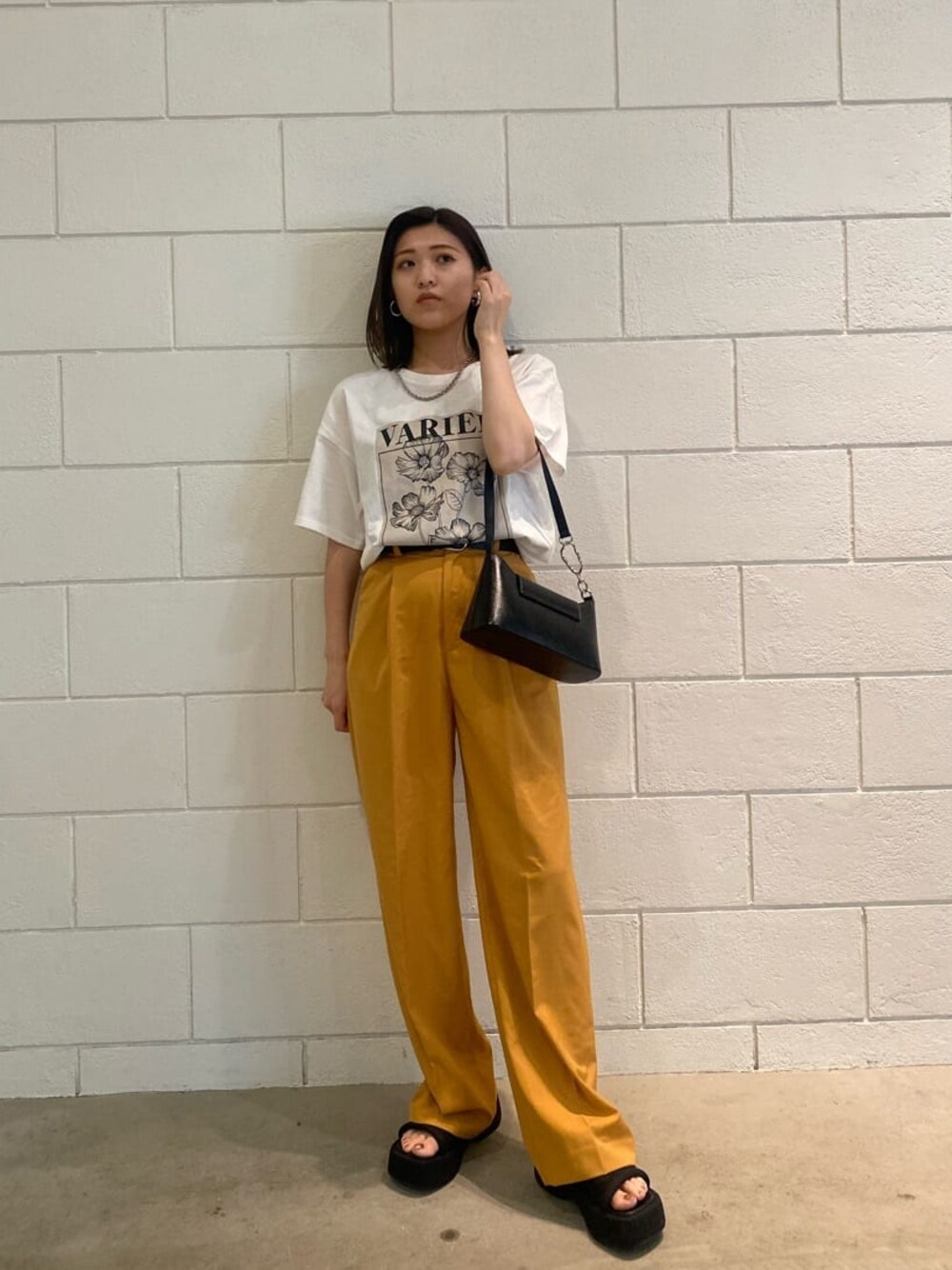 オレンジ系のその他パンツ、ブラック系のハンドバッグ、ホワイト系のTシャツ/カットソーを着用したレディースの春コーディネートの1枚目の写真