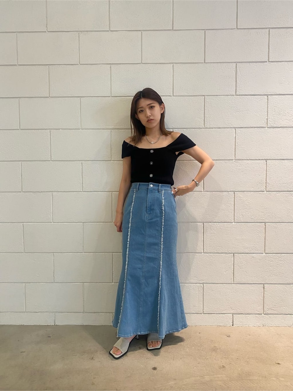 ブラウン系のハンドバッグ、ブルー系のスカート、ブラック系のタンクトップを着用したレディースの夏コーディネートの1枚目の写真