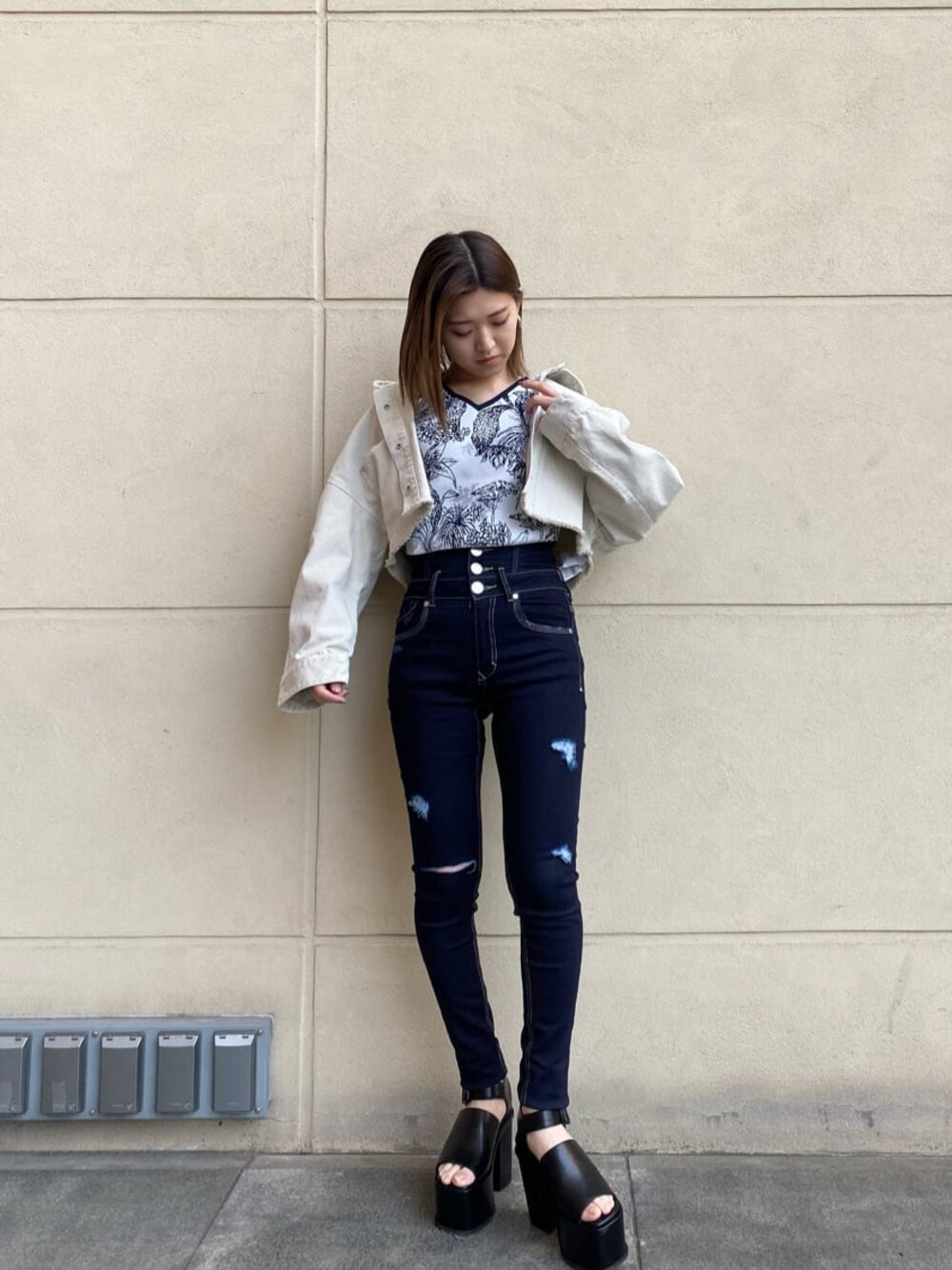 ブルー系のデニムパンツ、ホワイト系のデニムジャケット、ブラック系のサンダルを着用したレディースの春コーディネートの1枚目の写真