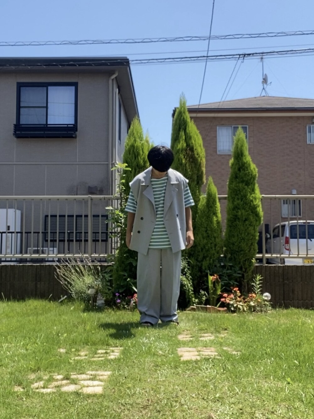 グレー系のスラックス、ブラック系のサンダル、グリーン系のTシャツ/カットソーを着用したメンズの夏コーディネートの1枚目の写真