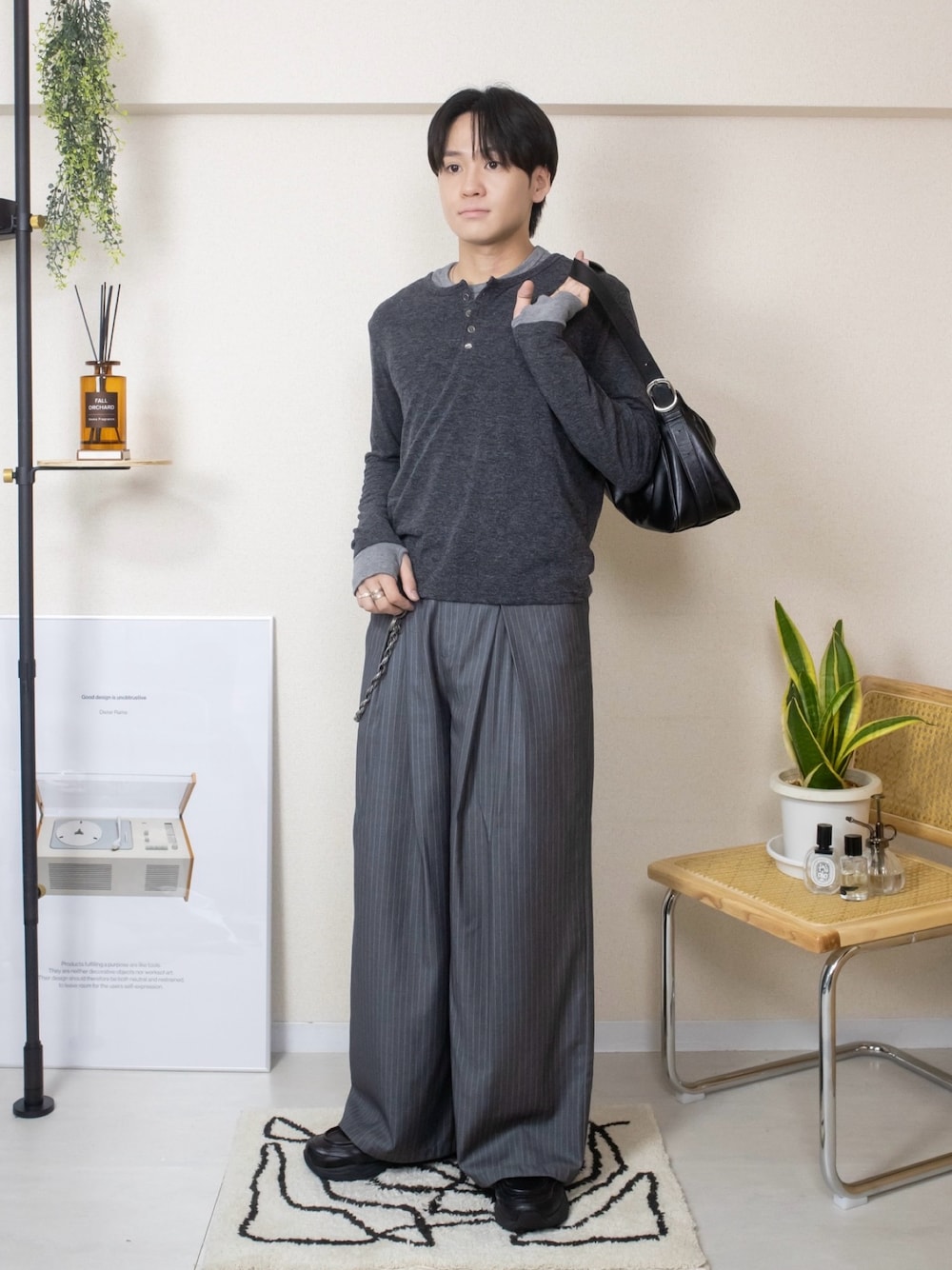 グレー系のスラックス、ブラック系のスニーカー、その他のTシャツ/カットソーを着用したメンズの秋コーディネートの1枚目の写真