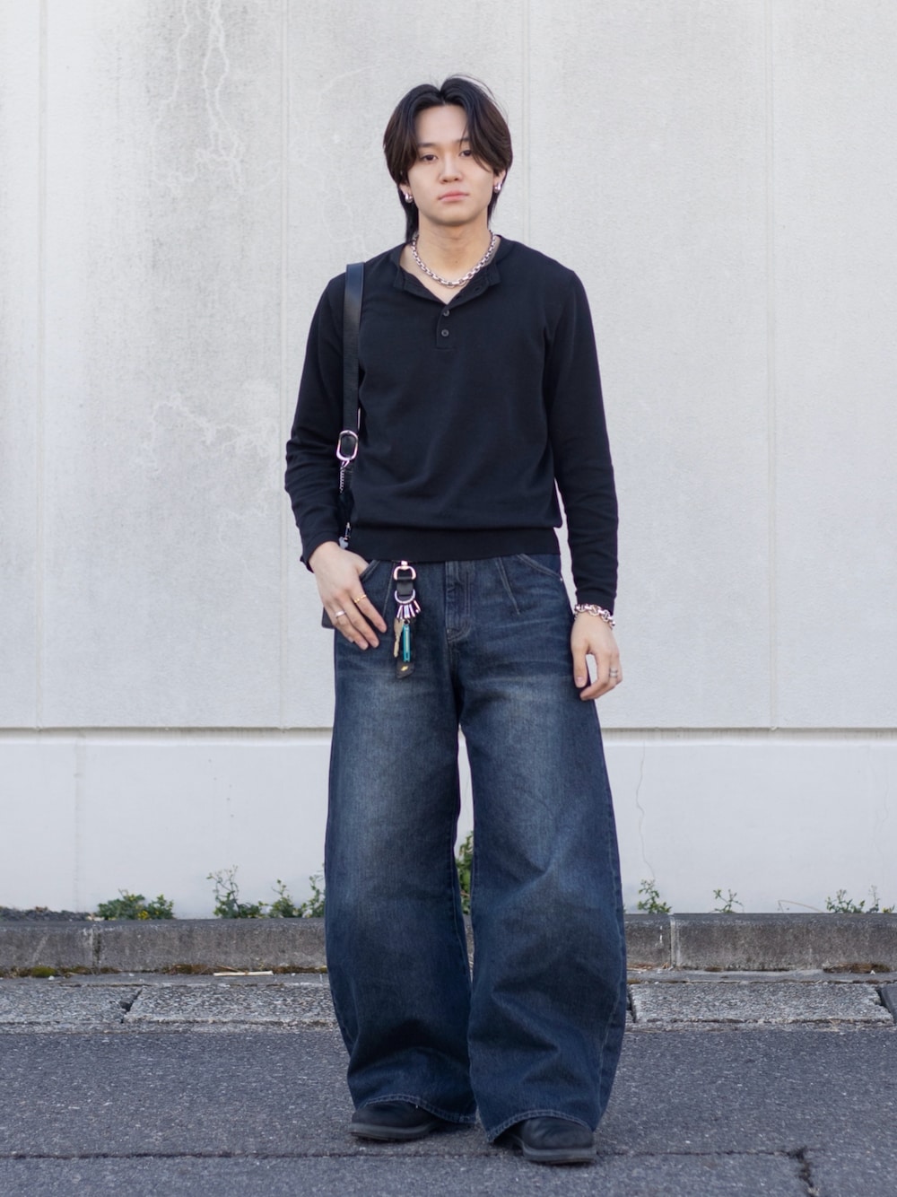 ブルー系のデニムパンツ、ブラック系のニット/セーター、ブラック系のドレスシューズを着用したメンズの春コーディネートの1枚目の写真