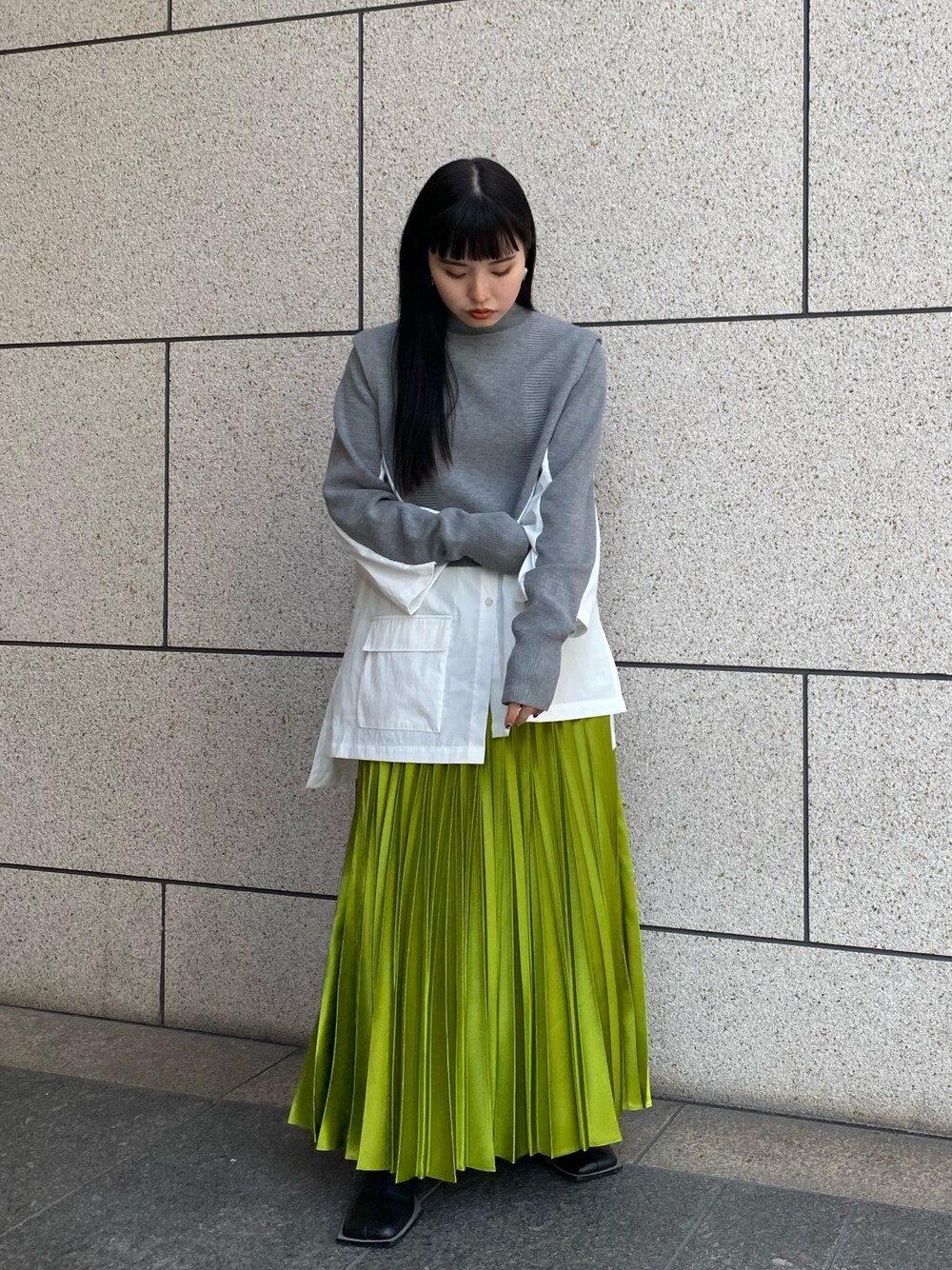 グレー系のニット/セーター、ブラック系のブーツ、グリーン系のスカートを着用したレディースの冬コーディネートの1枚目の写真