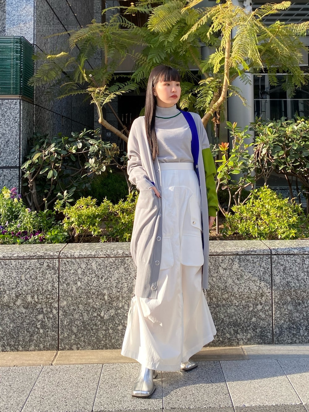 グレー系のニット/セーター、グレー系のカーディガン/ボレロ、ホワイト系のスカートを着用したレディースの冬コーディネートの1枚目の写真