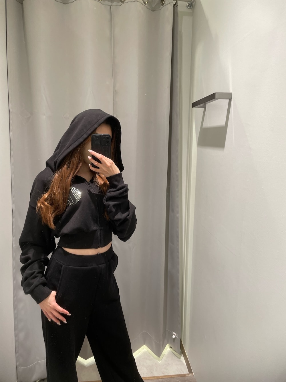ホワイト系のスニーカー、ブラック系のスウェットパンツ、ブラック系のパーカーを着用したレディースの冬コーディネートの1枚目の写真