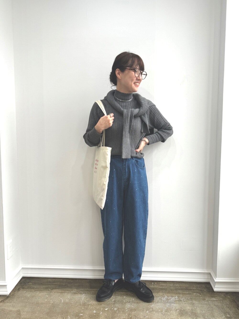 グレー系のニット/セーター、ブルー系のデニムパンツを着用したレディースの秋コーディネートの1枚目の写真