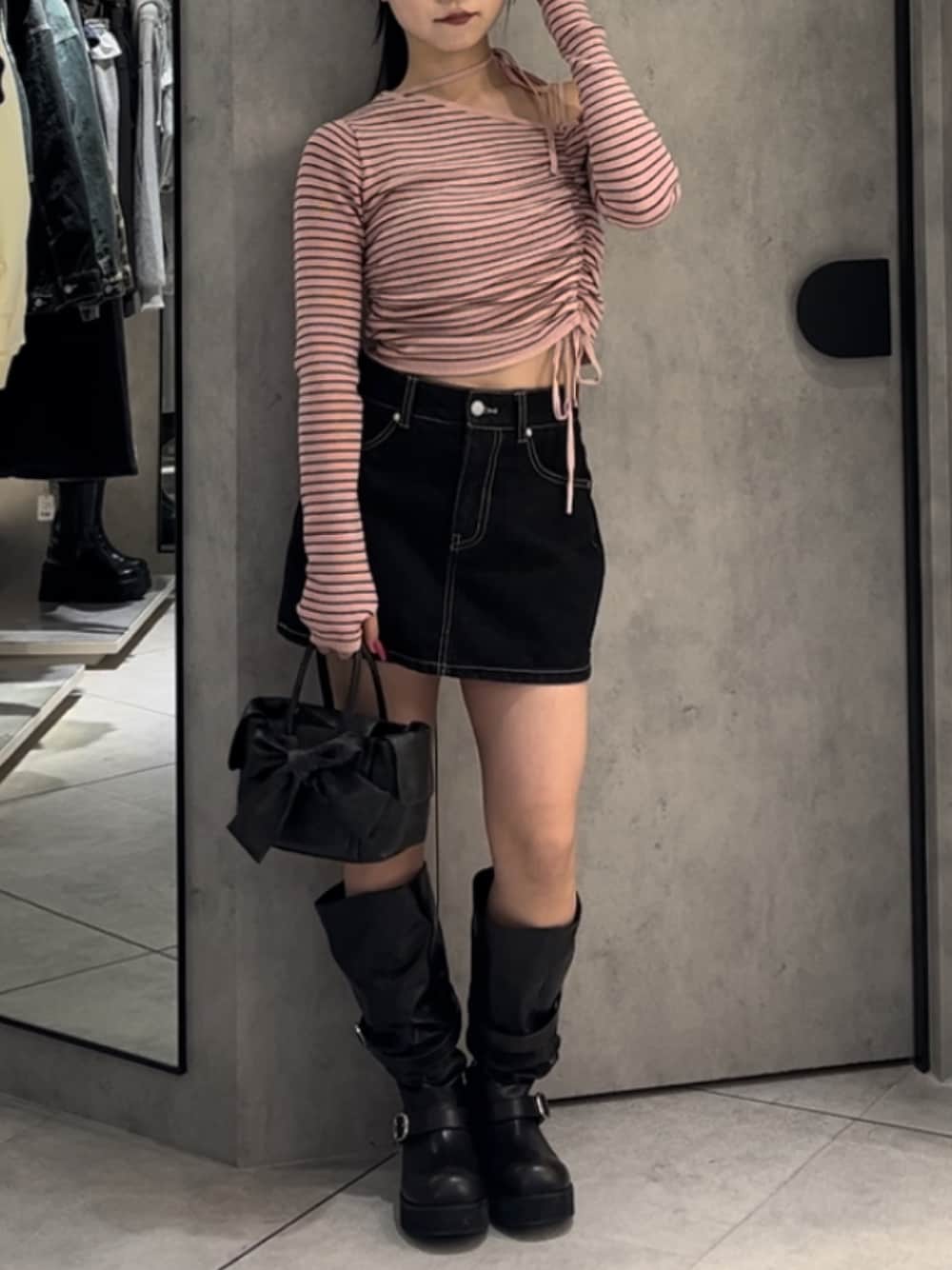 ピンク系のニット/セーター、ブルー系のスカート、ブラウン系のハンドバッグを着用したレディースの冬コーディネートの1枚目の写真