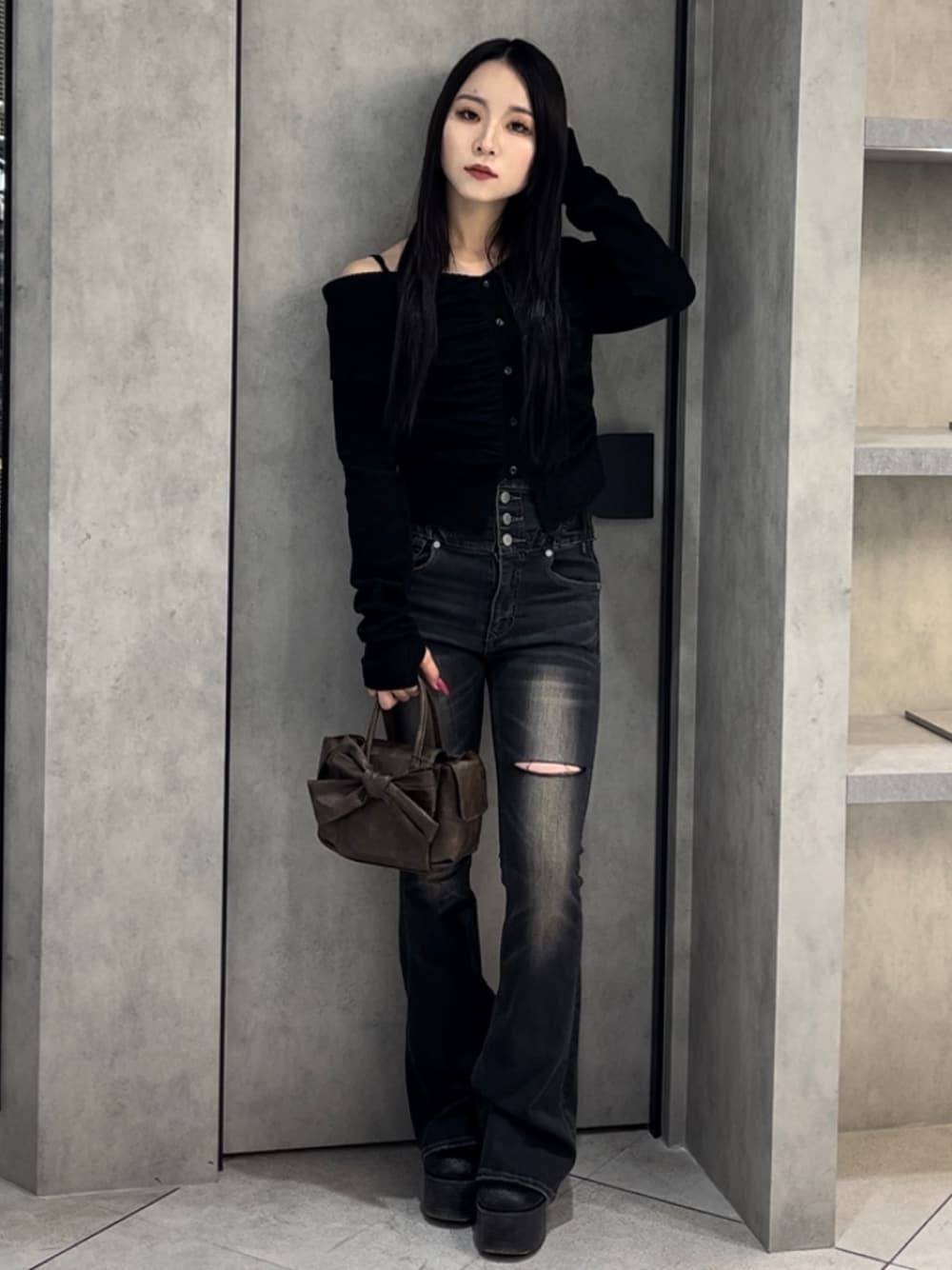 ブラック系のニット/セーター、ブラック系のデニムパンツ、ブラウン系のハンドバッグを着用したレディースの冬コーディネートの1枚目の写真