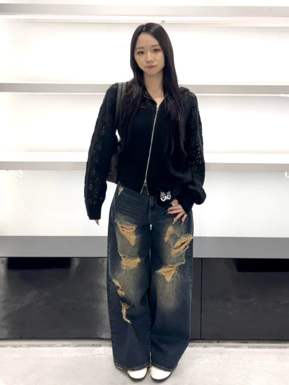 ホワイト系のスニーカー、ブルー系のデニムパンツ、ブラック系のパーカーを着用したレディースの春コーディネートの1枚目の写真