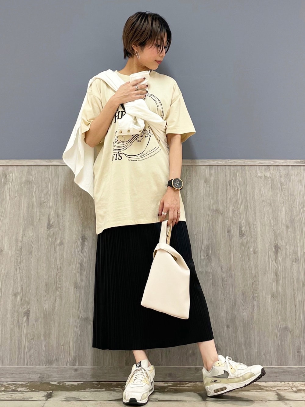 ホワイト系のショルダーバッグ、ブラック系のスカート、ベージュ系のTシャツ/カットソーを着用したレディースの夏コーディネートの1枚目の写真