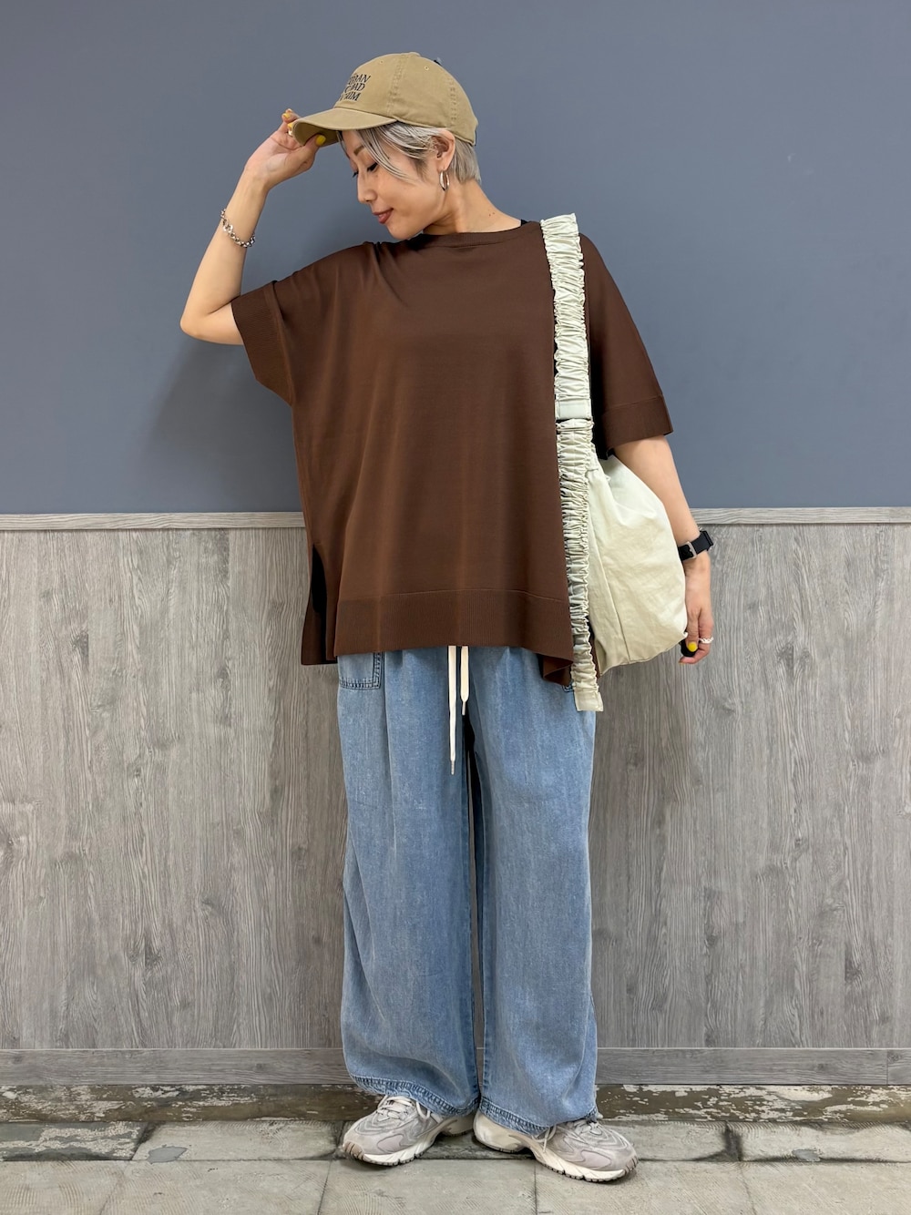 ブラウン系のニット/セーター、ブルー系のデニムパンツ、ベージュ系のキャップを着用したレディースの夏コーディネートの1枚目の写真