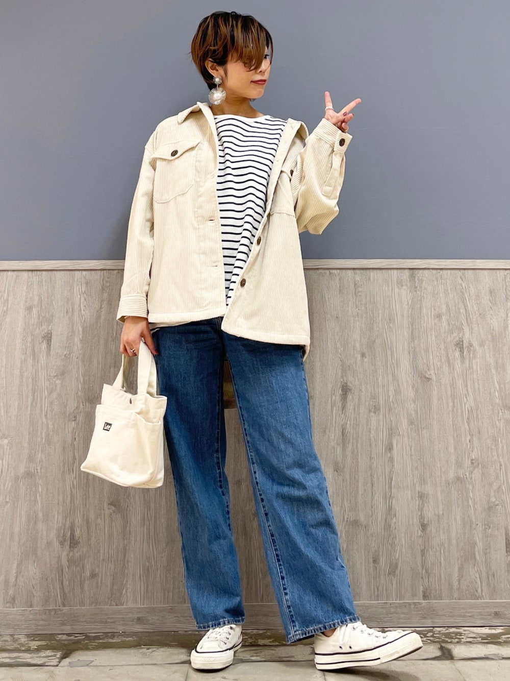 ホワイト系のトートバッグ、ブルー系のパンツ、ホワイト系のスニーカーを着用したレディースの秋コーディネートの1枚目の写真