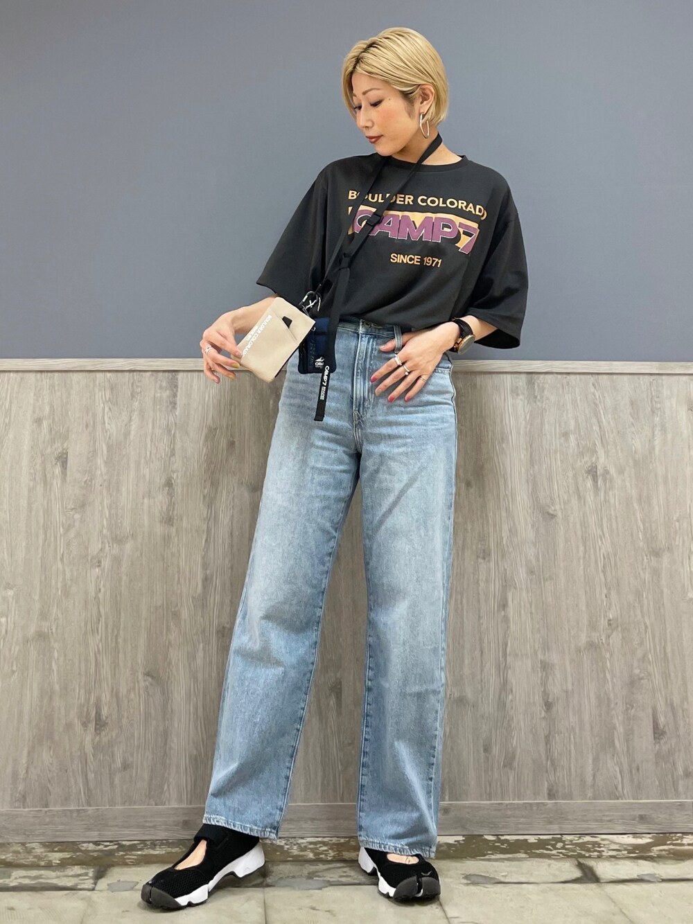 グレー系のTシャツ/カットソー、ベージュ系のショルダーバッグ、ブルー系のデニムパンツを着用したレディースの春コーディネートの1枚目の写真