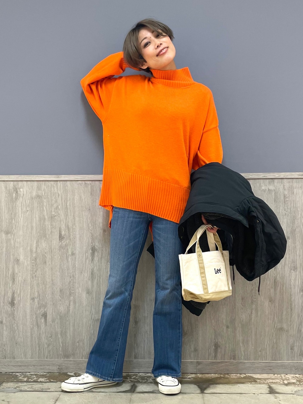 オレンジ系のニット/セーター、ブラック系のその他アウター、ベージュ系のトートバッグを着用したレディースの冬コーディネートの1枚目の写真