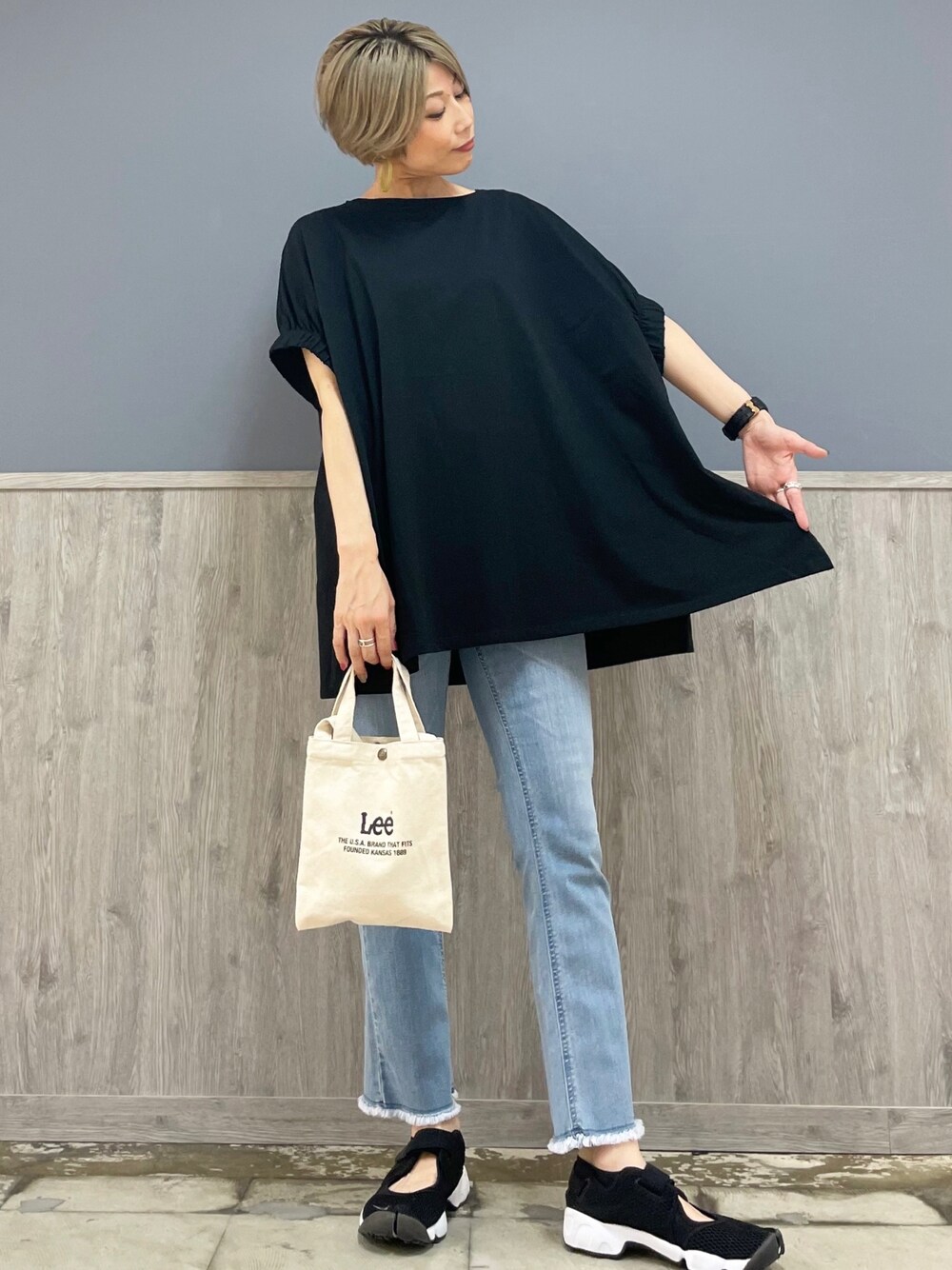 ブラック系のトップス、ブルー系のデニムパンツ、ブラック系のショルダーバッグを着用したレディースの夏コーディネートの1枚目の写真