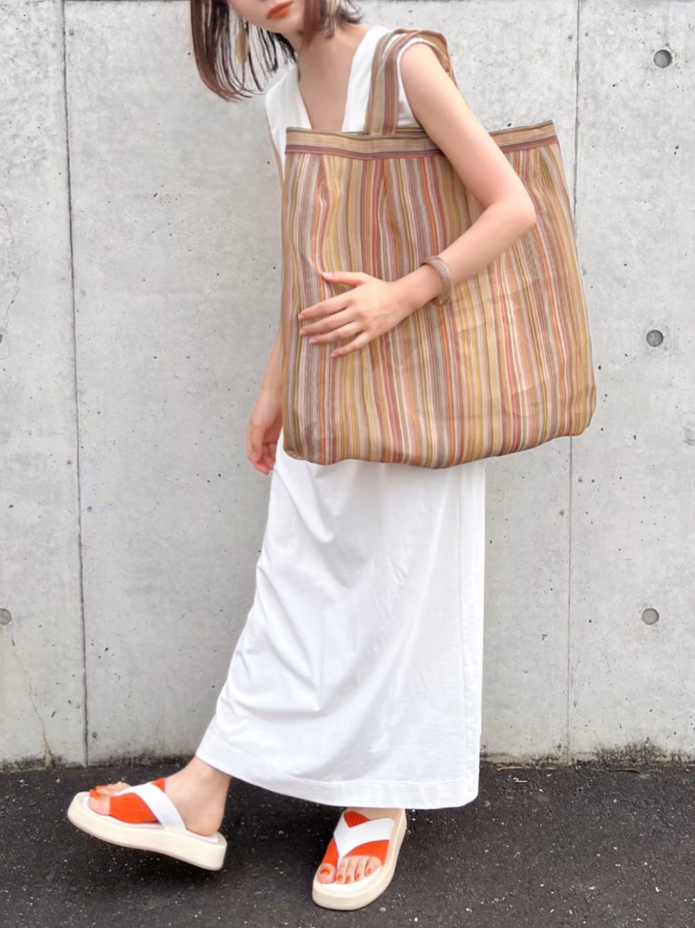 イエロー系のトートバッグ、ホワイト系のサンダル、ホワイト系のワンピースを着用したレディースの夏コーディネートの1枚目の写真