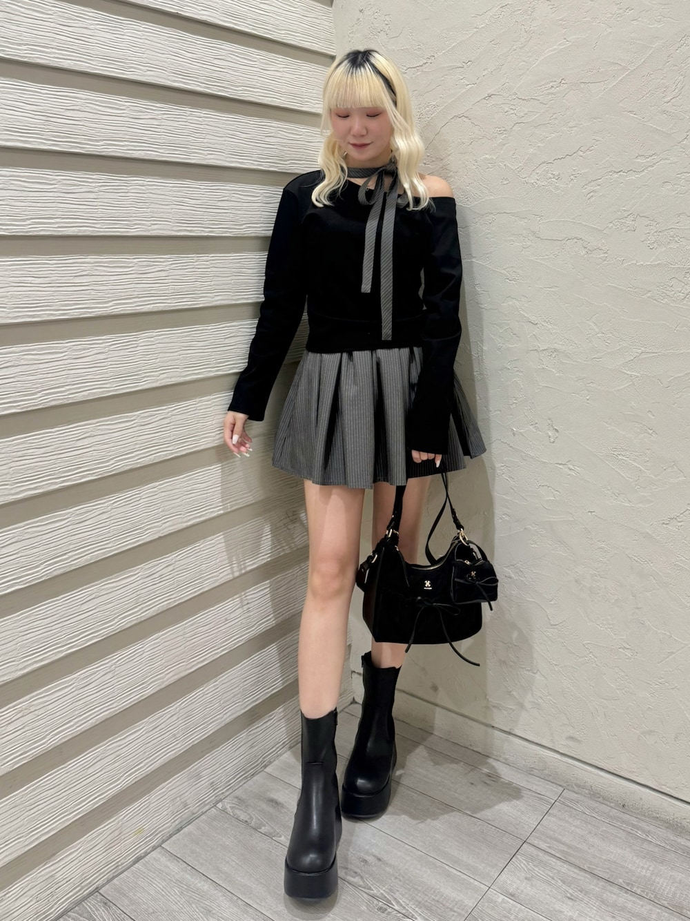 ブラック系のショルダーバッグ、グレー系のスカート、ブラック系のTシャツ/カットソーを着用したレディースの冬コーディネートの1枚目の写真