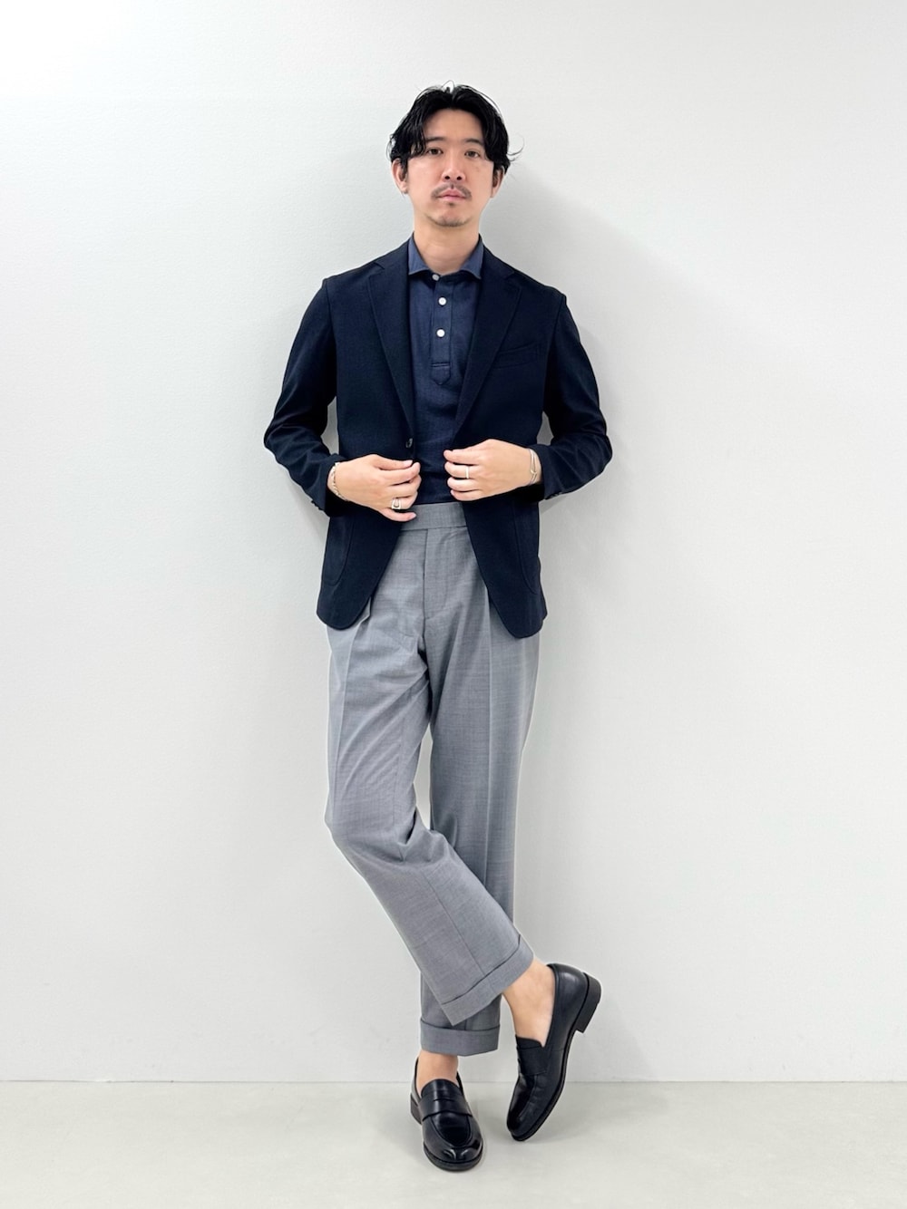 ブルー系のテーラードジャケット、ブルー系のポロシャツ、グレー系のスラックスを着用したメンズの春コーディネートの1枚目の写真