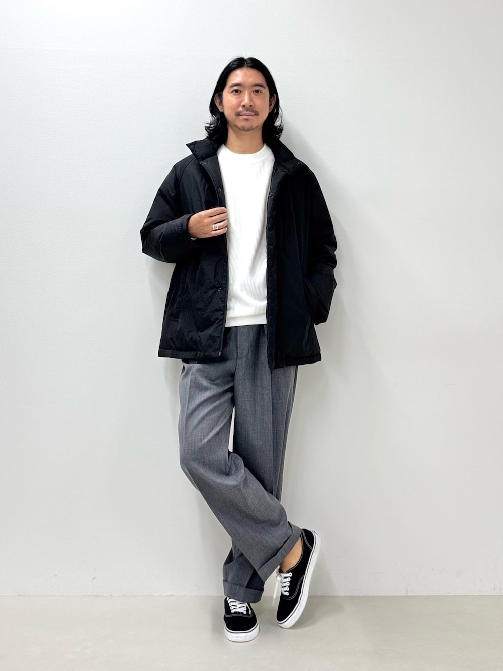 ホワイト系のTシャツ/カットソー、ブラック系のダウンジャケット/コート、グレー系のスラックスを着用したメンズの秋コーディネートの1枚目の写真