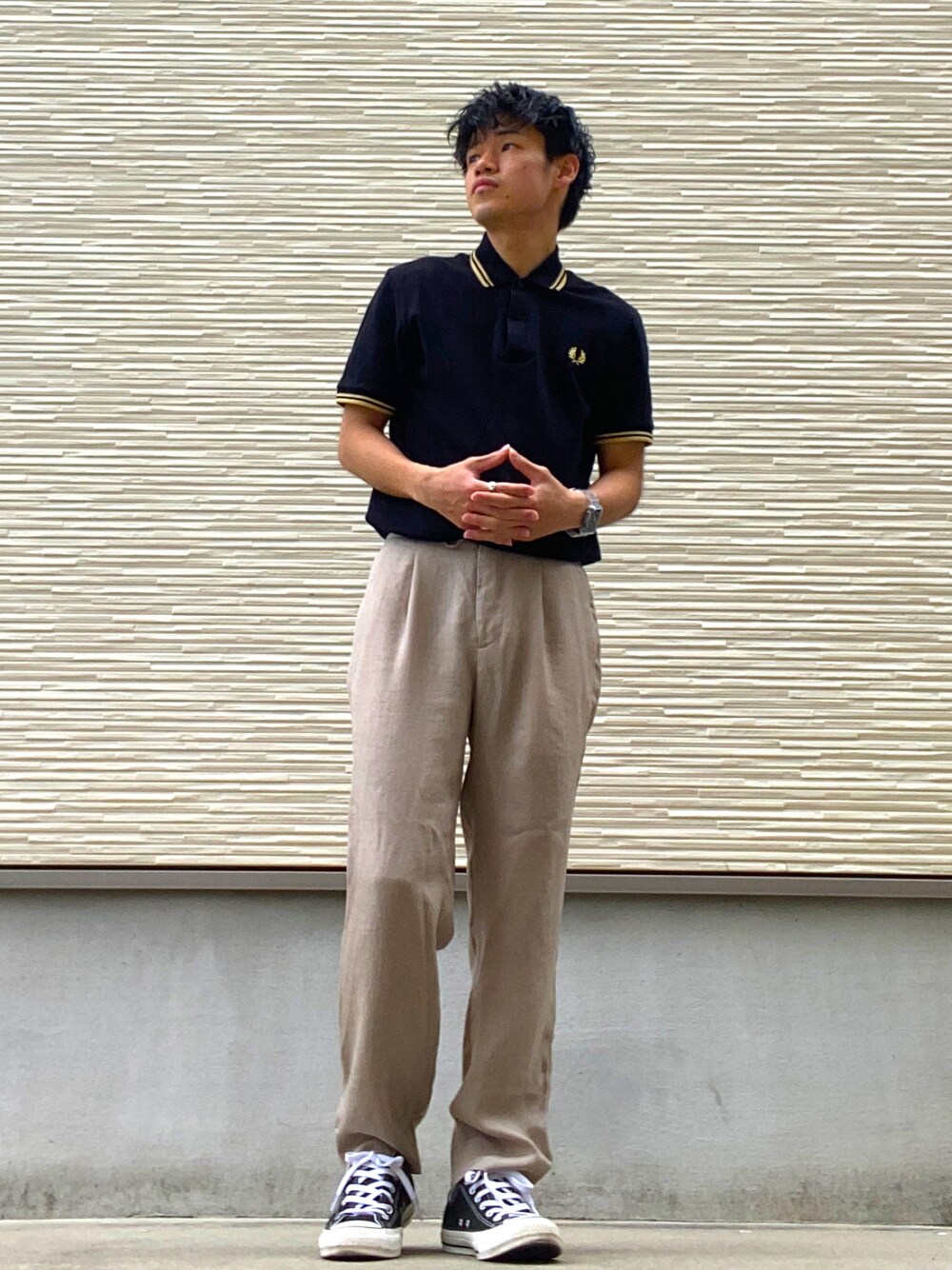 ブラック系のポロシャツ、ブラック系のスニーカー、ベージュ系のその他パンツを着用したメンズの夏コーディネートの1枚目の写真