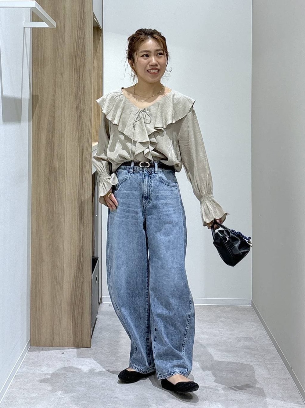ブルー系のデニムパンツ、ブラック系のパンプス、ブラック系のボストンバッグを着用したレディースの春コーディネートの1枚目の写真