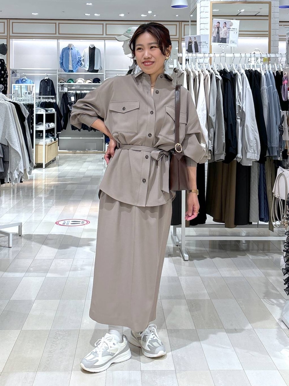 ブラウン系のショルダーバッグ、ブラウン系のスカート、ホワイト系のスニーカーを着用したレディースの春コーディネートの1枚目の写真