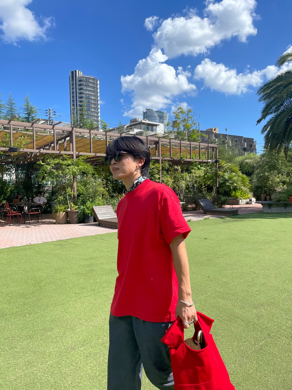 レッド系のTシャツ/カットソー、レッド系のハンドバッグ、ブラウン系のサングラスを着用したメンズの夏コーディネートの1枚目の写真