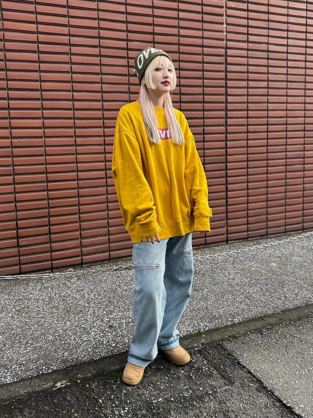 イエロー系のスウェット、ブルー系のデニムパンツ、ブラウン系のスニーカーを着用したレディースの冬コーディネートの1枚目の写真
