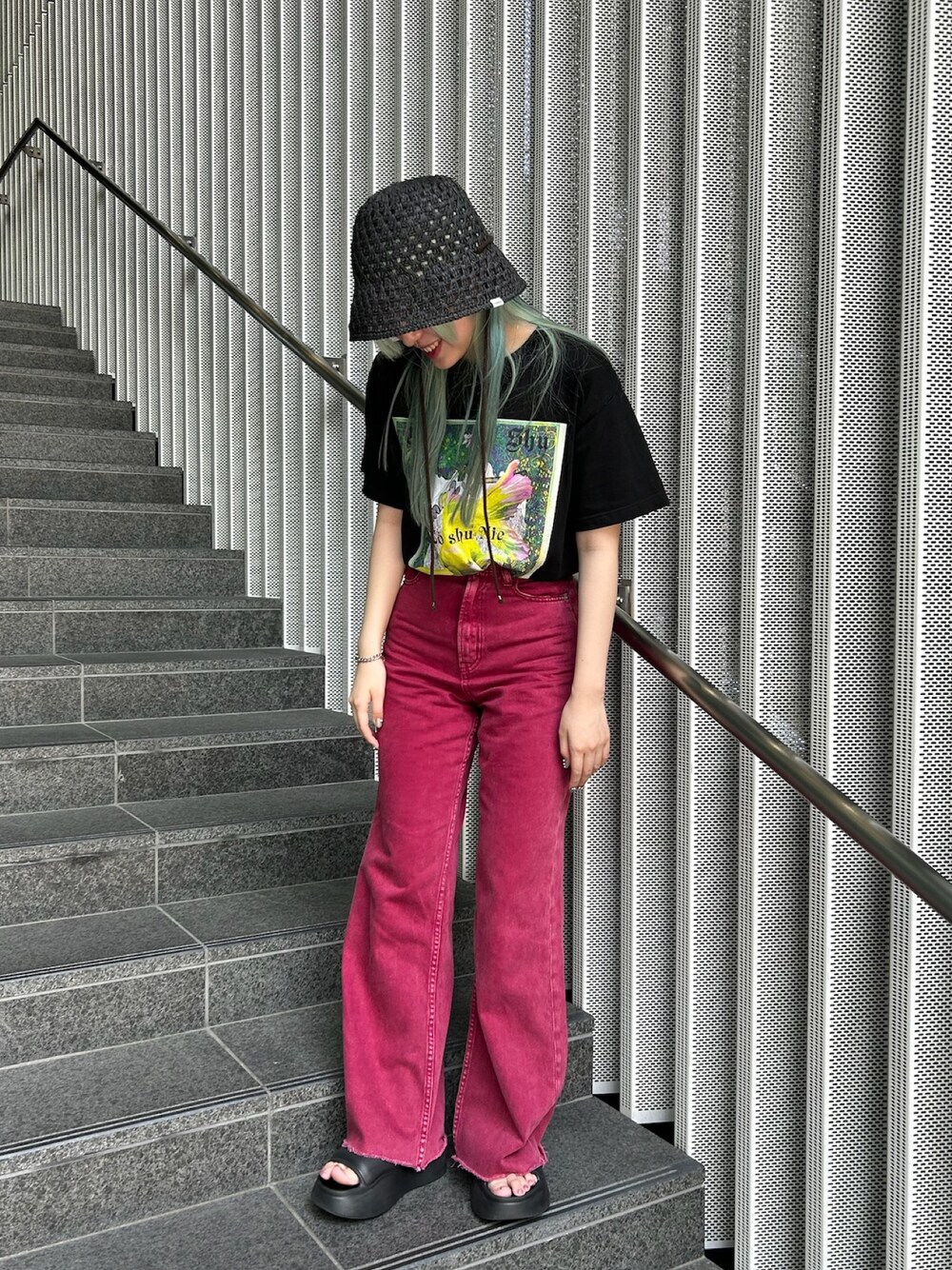 レッド系のデニムパンツ、ブラック系のサンダル、ブラック系のハットを着用したレディースの夏コーディネートの1枚目の写真
