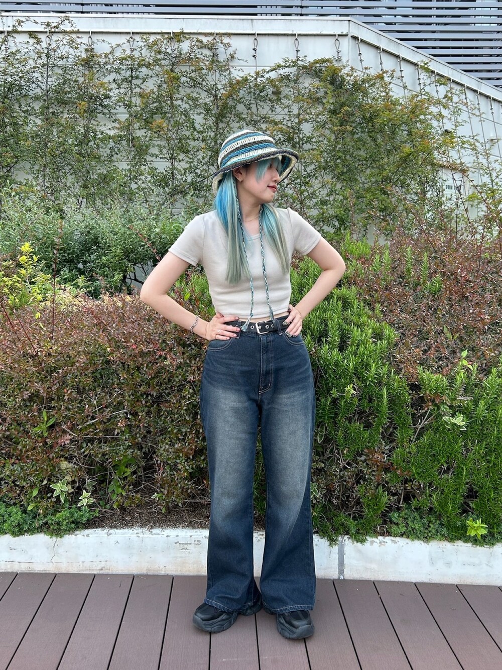 ブルー系のデニムパンツ、ブラック系のスニーカー、ブルー系のハットを着用したレディースの春コーディネートの1枚目の写真