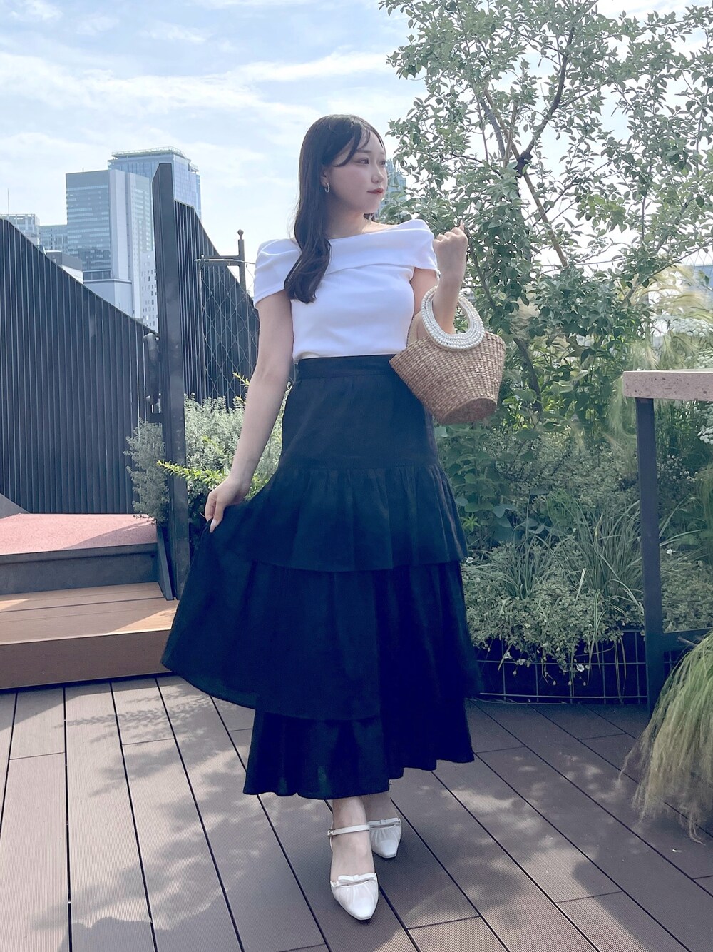 ブラック系のスカート、ベージュ系のかごバッグ、ホワイト系のTシャツ/カットソーを着用したレディースの夏コーディネートの1枚目の写真