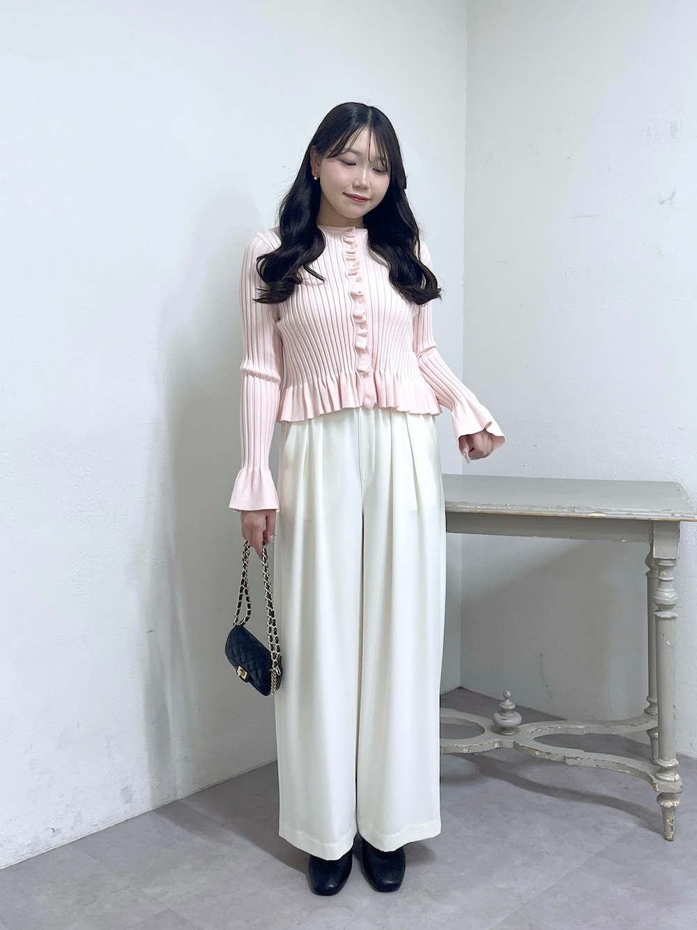 ピンク系のニット/セーター、ホワイト系のスラックス、ブラック系のブーツを着用したレディースの秋コーディネートの1枚目の写真