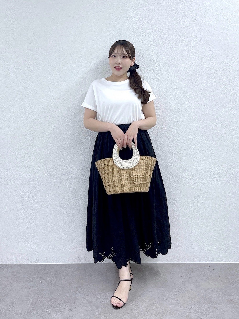 ブラック系のスカート、ベージュ系のかごバッグ、ホワイト系のTシャツ/カットソーを着用したレディースの夏コーディネートの1枚目の写真