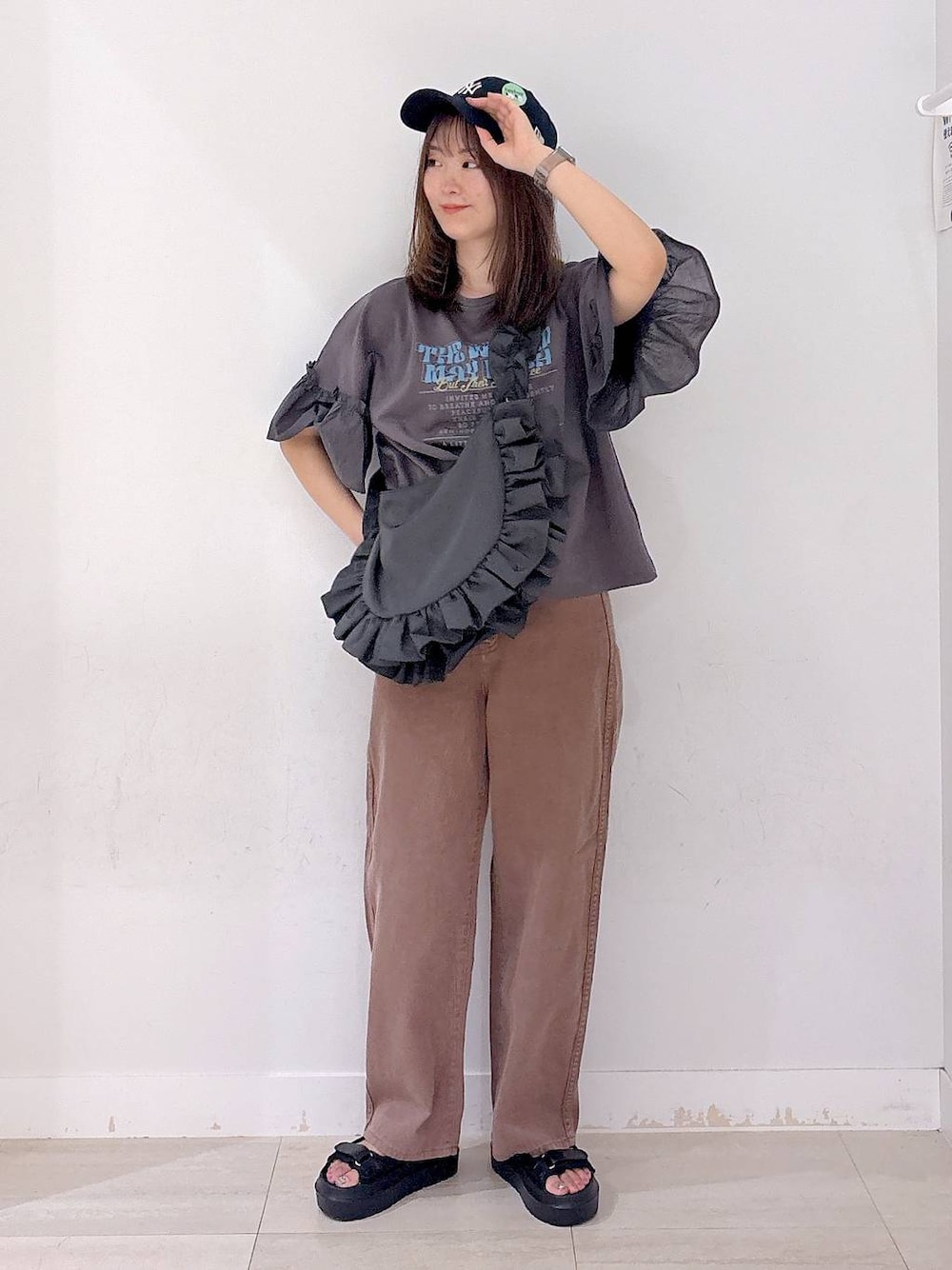 グレー系のショルダーバッグ、ブラウン系のデニムパンツ、ブラック系のサンダルを着用したレディースの秋コーディネートの1枚目の写真