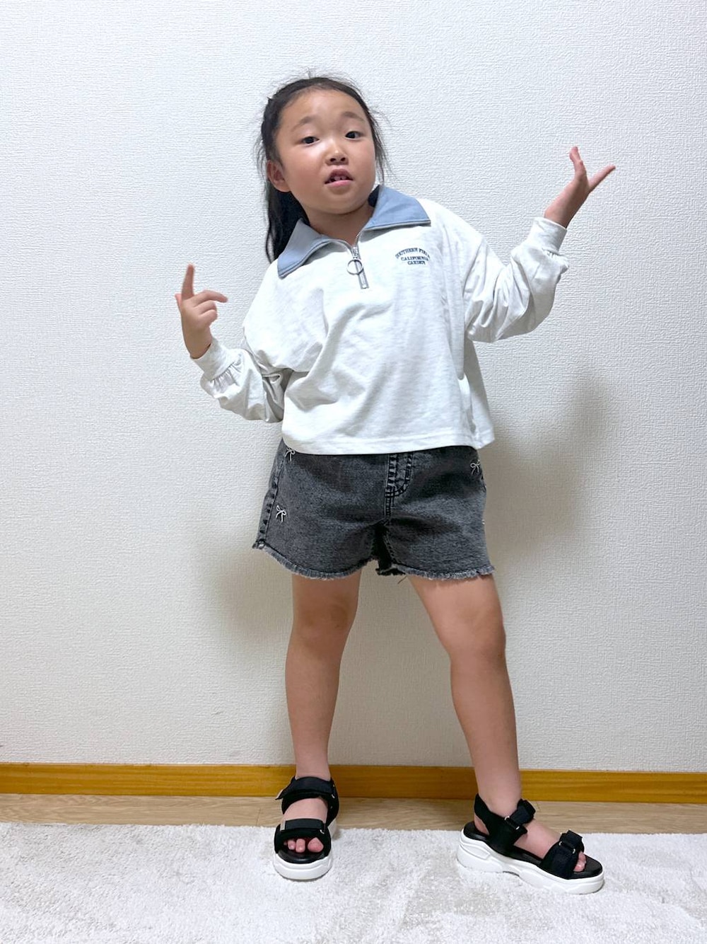 ブラック系のデニムパンツ、ブラック系のサンダル、グレー系のTシャツ/カットソーを着用したキッズの秋コーディネートの1枚目の写真