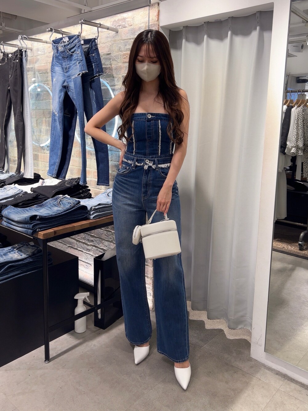 ブルー系のチューブトップ、ブルー系のデニムパンツ、ホワイト系のハンドバッグを着用したレディースの春コーディネートの1枚目の写真